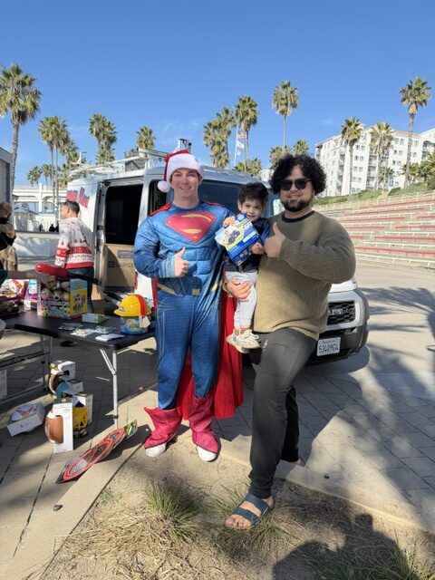 Parent and child smiling with The Plumber Man at toy drive